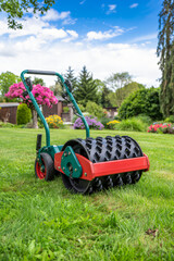 Fototapeta premium garden roller aerator resting on freshly aerated lawn