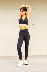 Fototapeta premium Full body young sports woman doing stretching exercise by wall