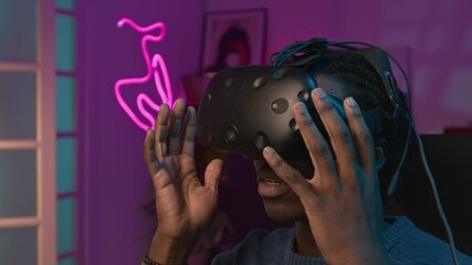 Closeup of face of cheerful young African American male influencer putting on augmented reality headset during live stream show on social media or online shop, describing his sensations to viewers