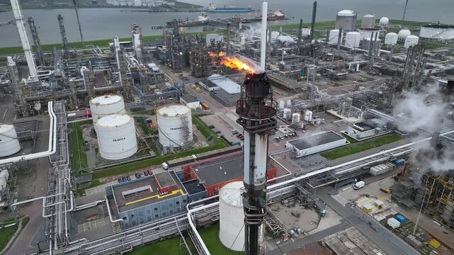 Aerial view of a chemical plant at sunset. Drone shot. Curling fire and cumin smoke filling the sky. Smoking chimneys from the factory. Chimneys of an oil refinery at sunrise pollute the environment