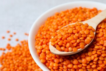 Red lentils in a spoon on a gray background
