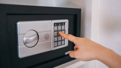 Close-up of a person hand entering a password to unlock and open the safe box door.