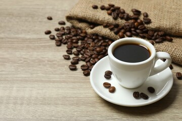 Cup of coffee with coffee beans on wooden background