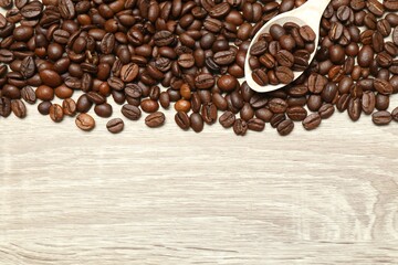 Coffee beans in a spoon on wooden background