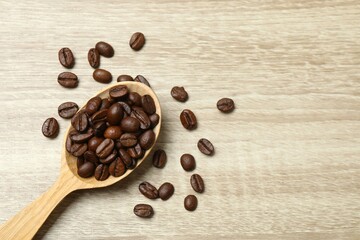 Coffee beans in a spoon on wooden background