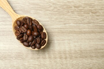 Coffee beans in a spoon on wooden background