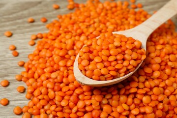 Red lentils in wooden spoon on a wooden background