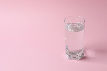 Glass of water on color background