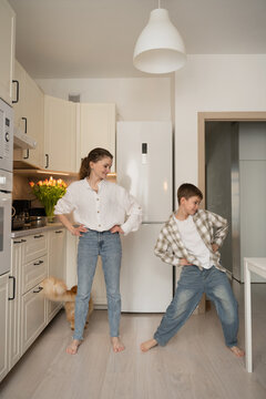 Mother and son dancing happily in the kitchen at home