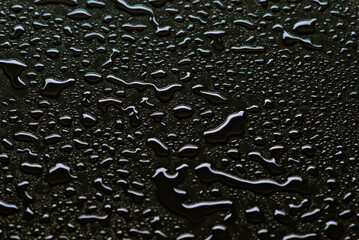 Shimmering raindrops on a dark reflective surface
