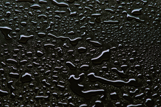 Shimmering raindrops on a dark reflective surface