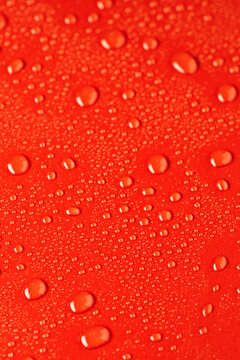 Water droplets on vibrant red surface create dynamic texture