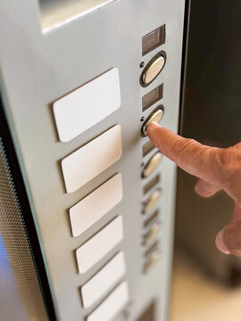 Person using elevator button panel indoors for access