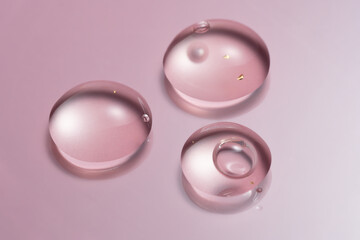 24K gold serum drops in petri dishes on pink backdrop