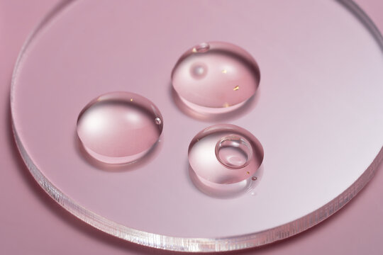 Elegant 24k gold serum drops on a petri dish, pink background