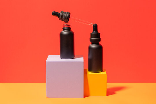 Minimalist black dropper bottles on colorful geometric blocks