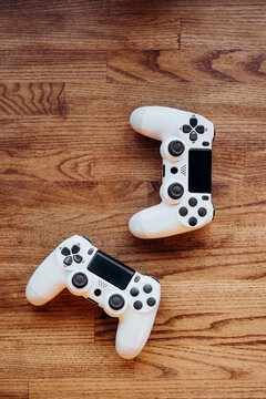 Two white gaming controllers on wooden surface for gaming fun