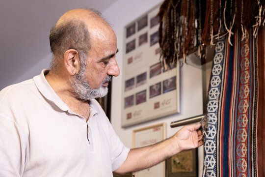 Iranian carpet restorer examines textiles in Salzburg workshop