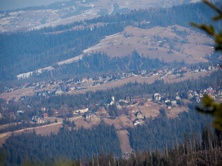 Aerial Panoramic View of Small Mountain Village Nestled in Valley Among Dense Forest and Rolling...