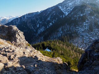 Rugged Mountain Cliff Edge with Rocky Outcrop Overlooking Snow-Dusted Valley and Peaks