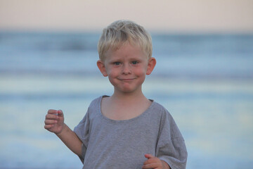 closeup portrait of cheerful toddler boy on the beach at dusk on summer evening 