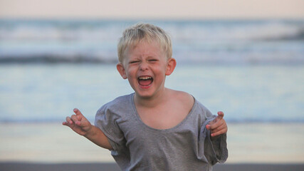 closeup portrait of screaming   excited toddler boy on the beach at dusk on summer evening  © atikinka2