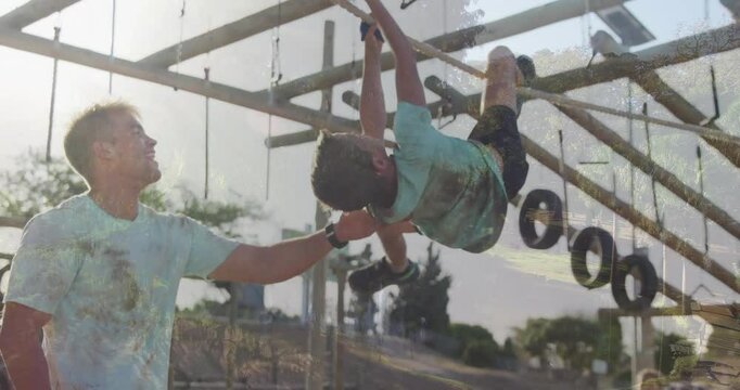 Helping child on monkey bars, father at playground with animation mural