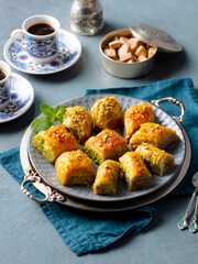 Baklava dessert on a silver tray and a cup of coffee. Grey background. Close up.