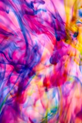 Abstract video with vibrant colors flowing with colored inks dispersed in water. The composition consists of shades of blue, red, green and yellow blending and swirling on a light background, creating