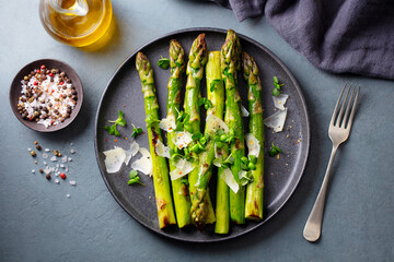 Cooked asparagus with parmesan cheese. Grey background. Close up. Top view.
