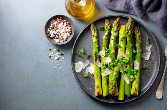 Cooked asparagus with parmesan cheese. Grey background. Copy space. Top view.