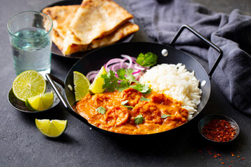 Kerala prawns curry in black bowl. Grey background. Close up.