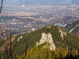 Aerial View of Mountain Valley Town Nestled Between Forest-Covered Slopes and Dramatic Rocky...