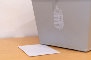 Ballot box with Hungarian state coat of arms and voting envelope on a table