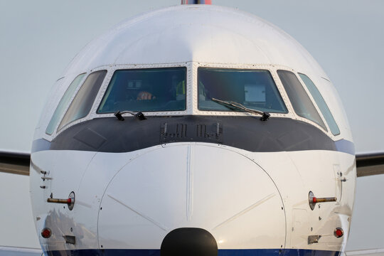 Front view of a commercial airplane cockpit with reflections on fuselage