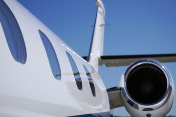Fototapeta premium Close-up of private jet exterior with engine and windows against clear blue sky