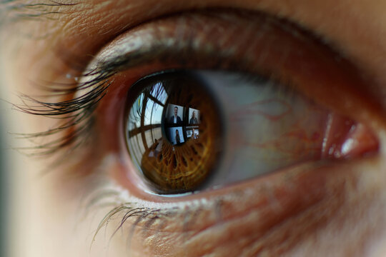Close-up of eye reflecting virtual meeting with diverse participants