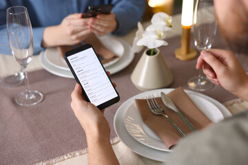 Couple choosing dishes from digital menu at restaurant, closeup