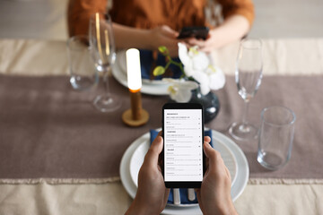Couple choosing dishes from digital menu at restaurant, above view