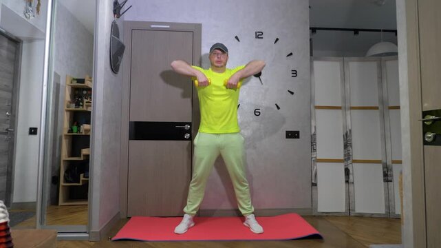 Train dumbbell shoulder joint on training at home. Men's workout a on a fitness mat. Slow motion