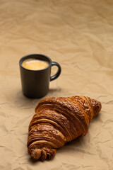 A cup of coffee with a croissant