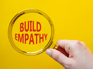 Build empathy symbol. Magnifying glass with words Build empathy. Beautiful yellow background....