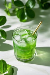 there is a glass of green liquid with a straw and a leaf
