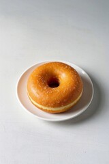 there is a donut on a plate on a white table