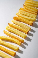 a close up of a row of french fries on a white surface