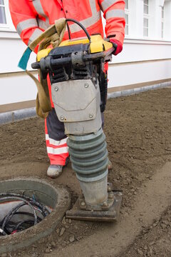 Bauarbeiter auf einer Baustelle mit einem Stampfer