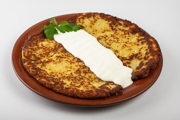 Traditional Belarusian or Ukrainian potato pancakes with fried meat, sauted vegetables, sour cream, cheese, mushroom sauce, and fresh herbs on a wooden platter