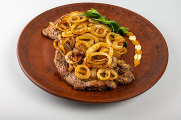 Grilled pork steak with golden fried onions served on a rustic clay plate. Traditional Eastern...