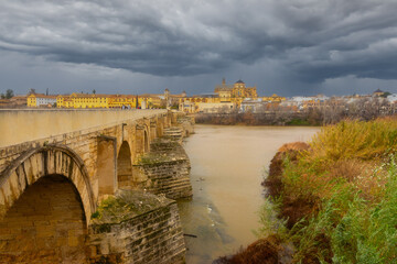 Puente Romano Old Roman Bridge Across Guadalqivir River Landscape, Cordoba Spain Historic Center Panorama, Dramatic Stormy Sky