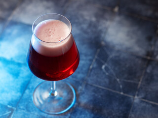 Glass of red ale on blue table. Craft beer. Copy space
